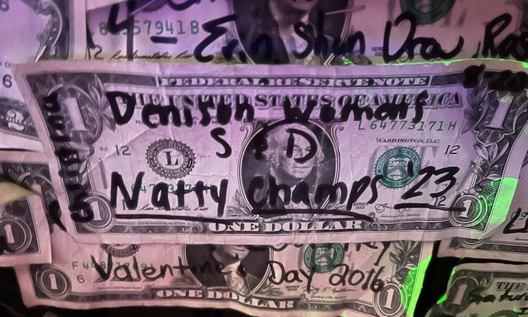 A dollar bill pasted on the wall that reads 'Denison Women’s S & D (Team) Natty Champs ’23'