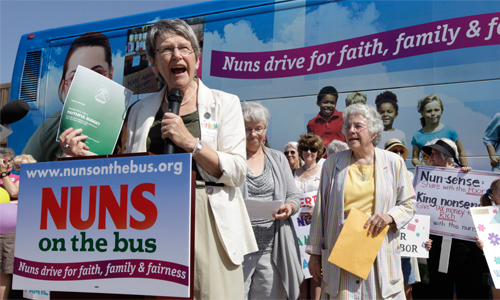 Sister Campbell in front of a sign reading 'Nuns on the bus'