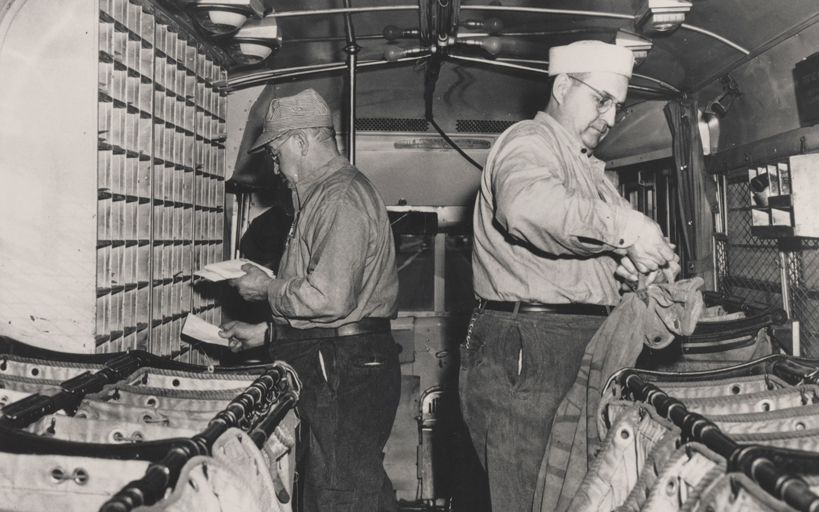 Two clerks sort mail inside the first Highway Post Office bus, which ran from Washington, D.C. to Harrisonburg, Va., during its inaugural year: 1941.