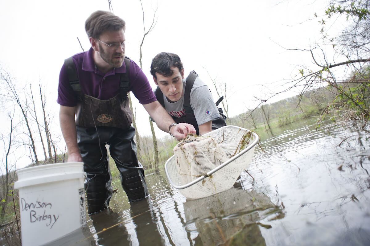 Professor and student collecting samples from the pond