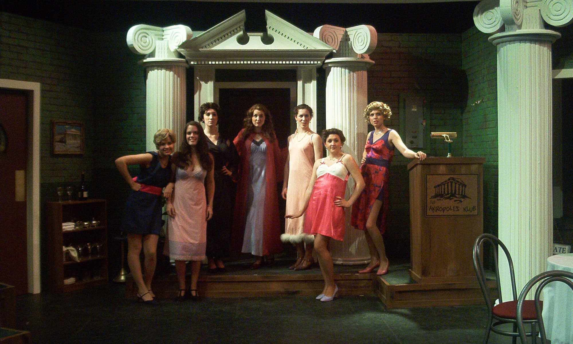 Lysistrata stands with the Athenian and Spartan women in front of the club entrance in nightgowns.