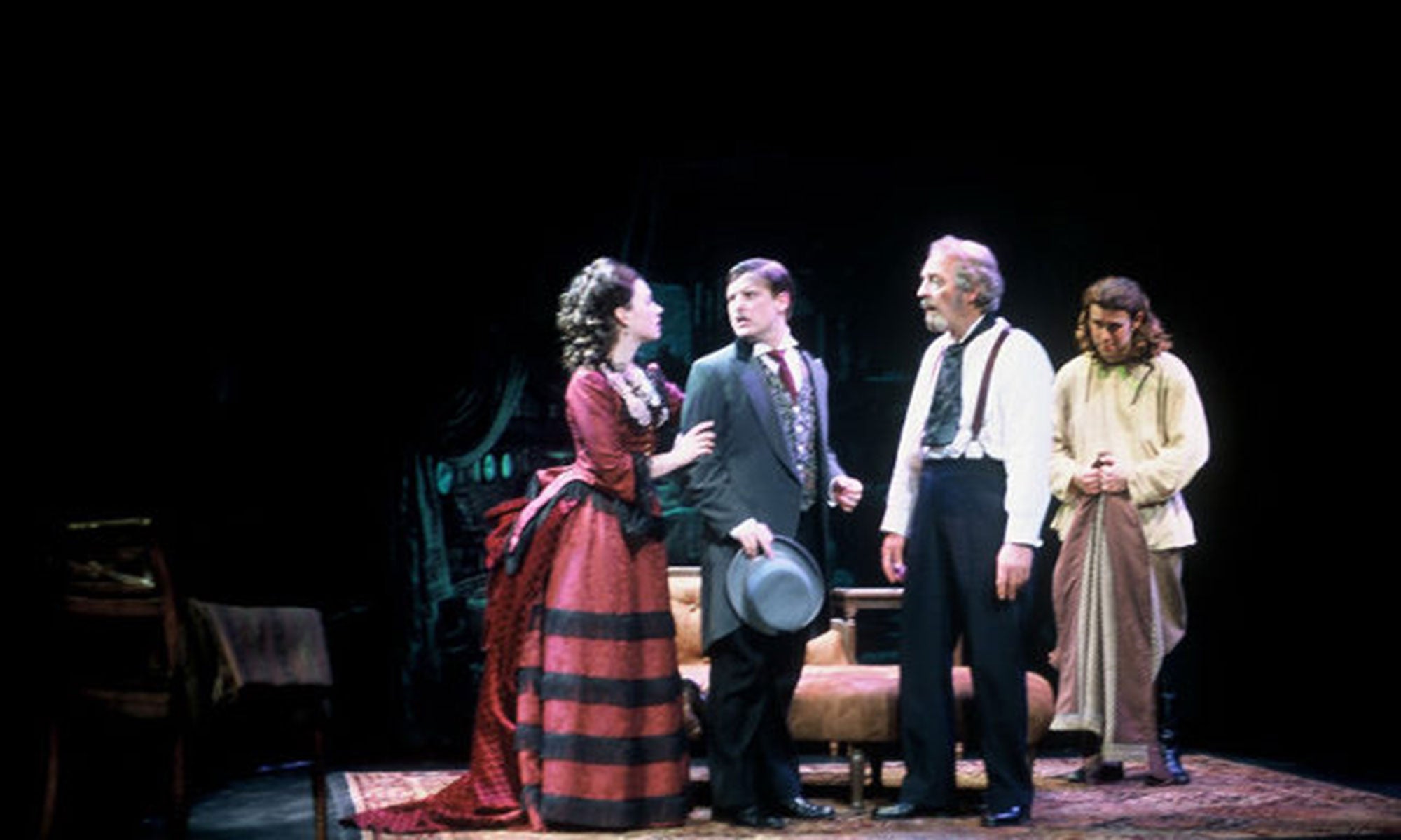 Praskovya holds the arm of her brother, who looks confused and worried at her. Ivan stands slackjawed, while the servant Gerasim watches him.