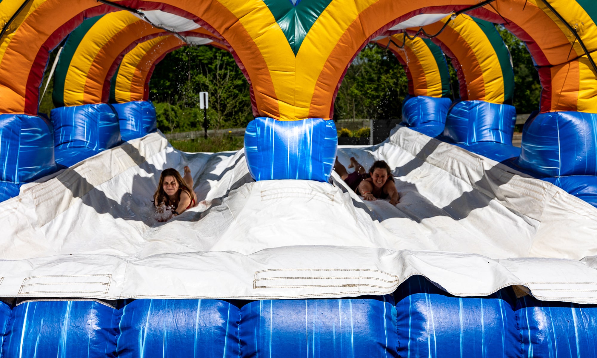 two people sliding down a giant slip n slide