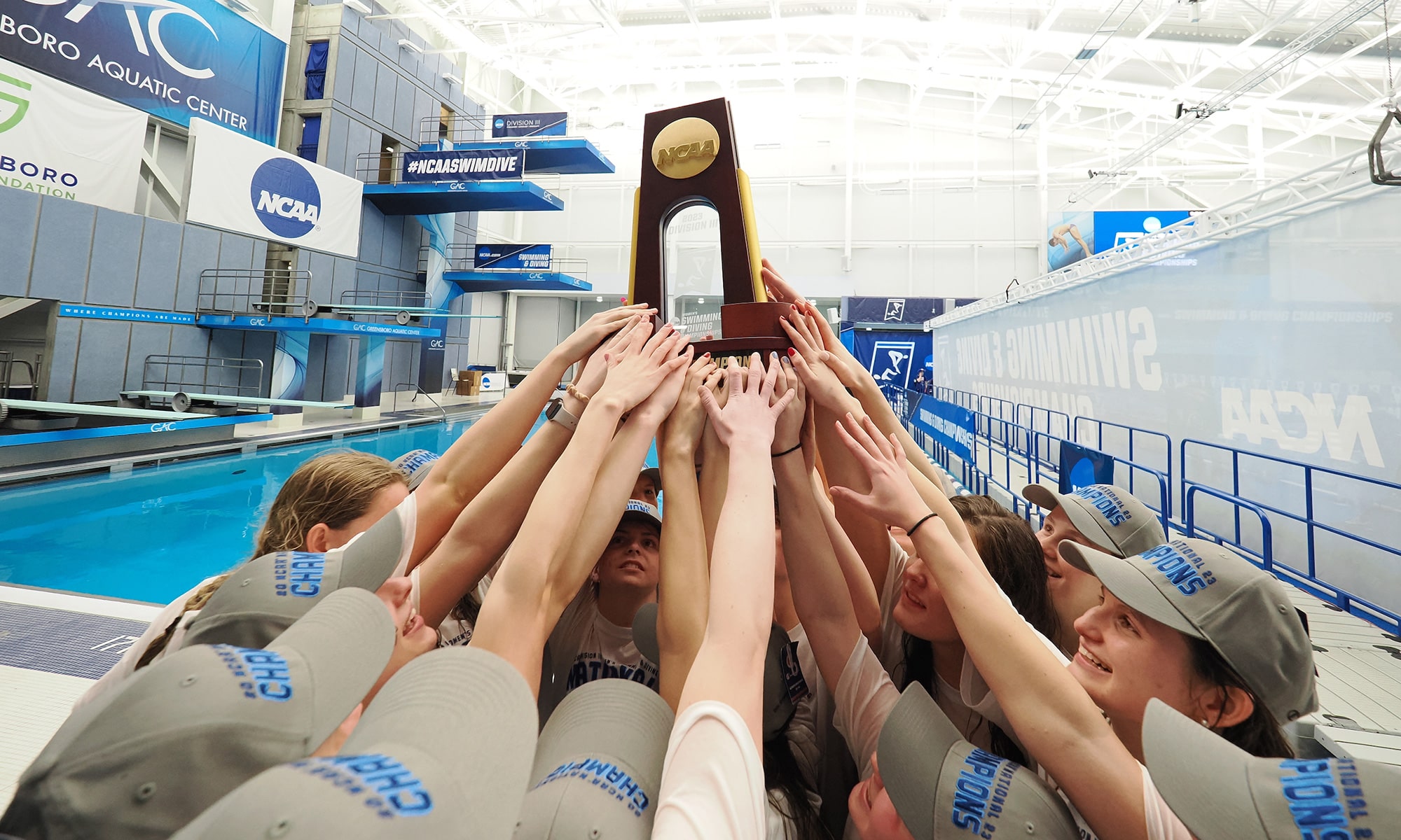 The Denison swim & dive team all hold up the championship trophy together