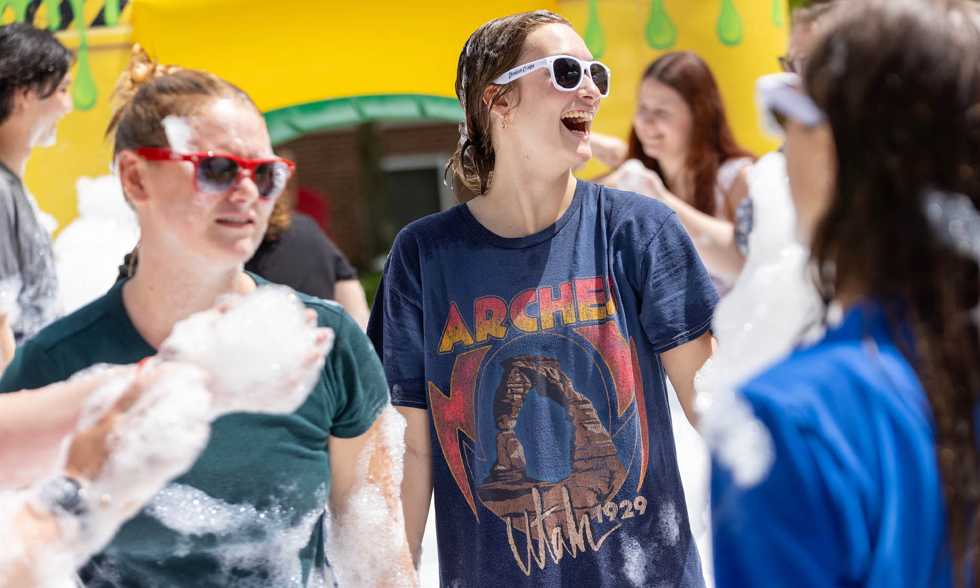 A student smiles along with other students as they play with mounds of soap bubbles.