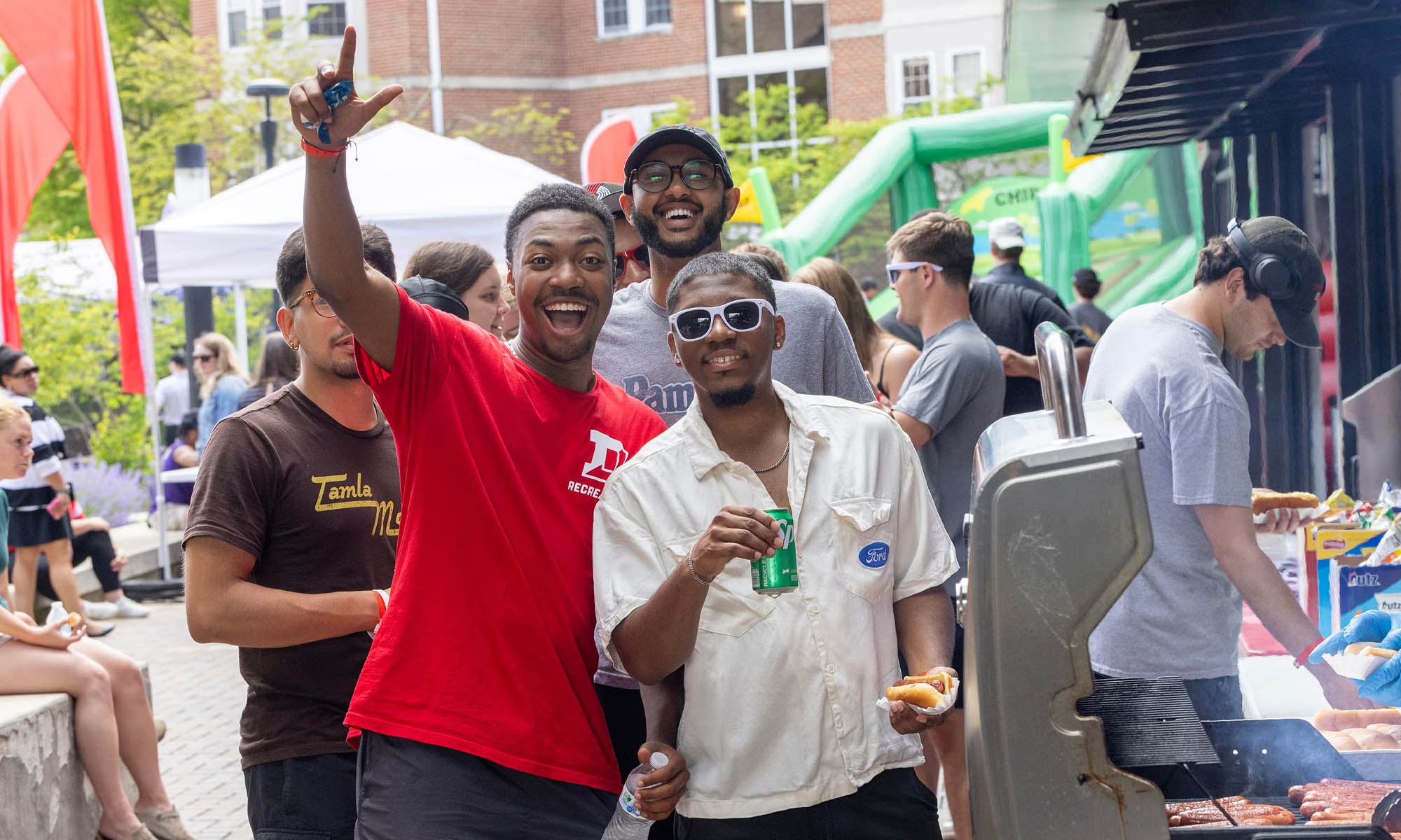 Students smiling and waving at a fun fair.