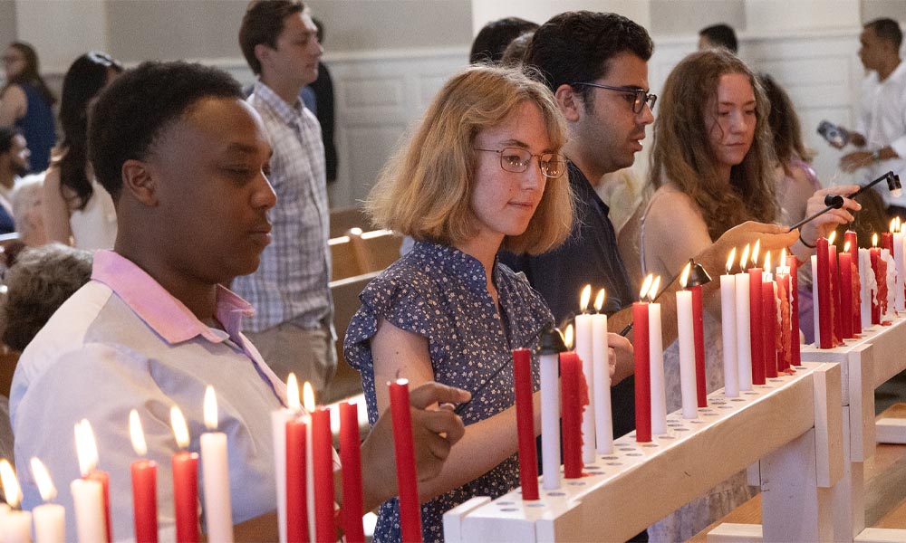 Students stand before a row of candles.
