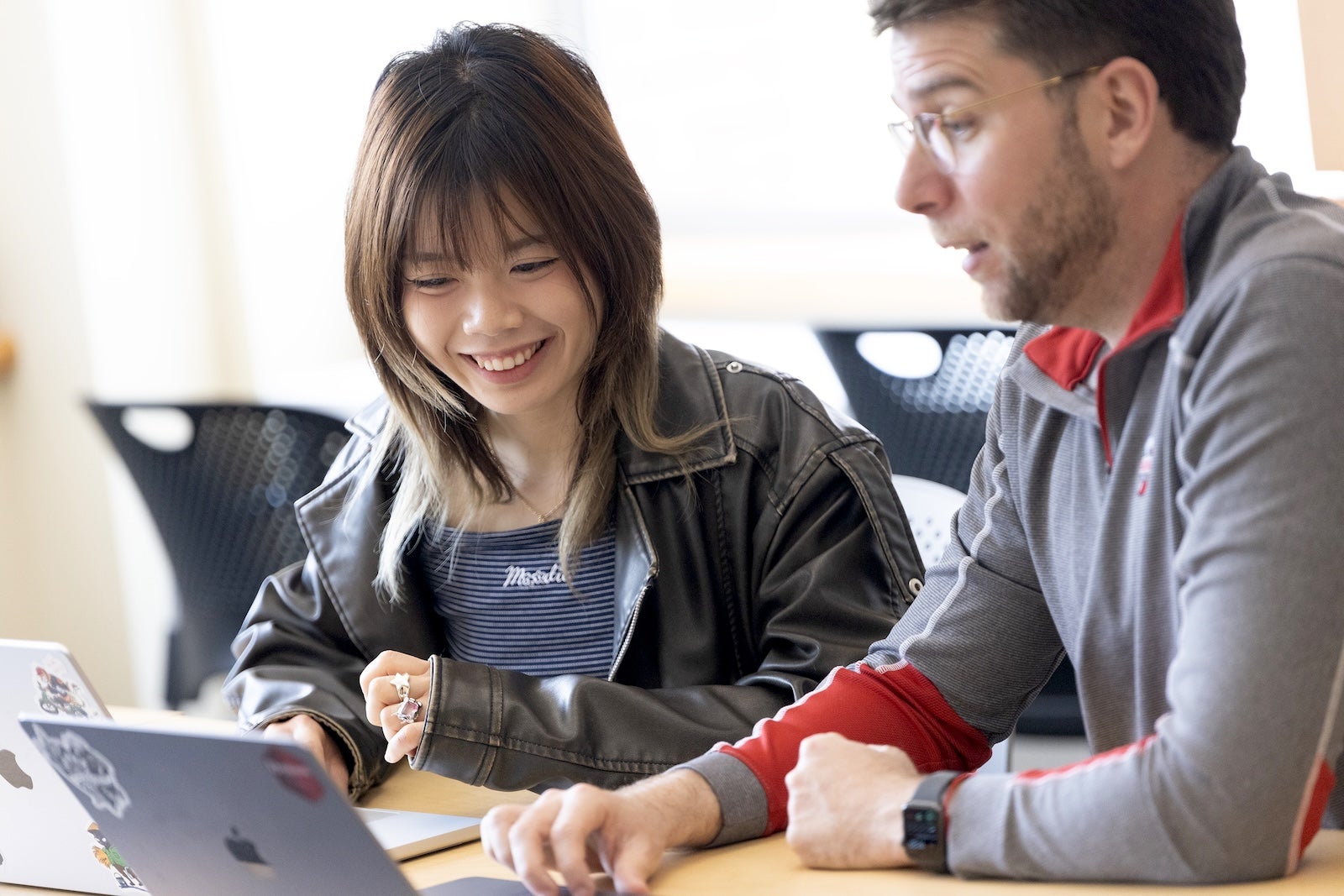 Student smiles as she works with faculty member
