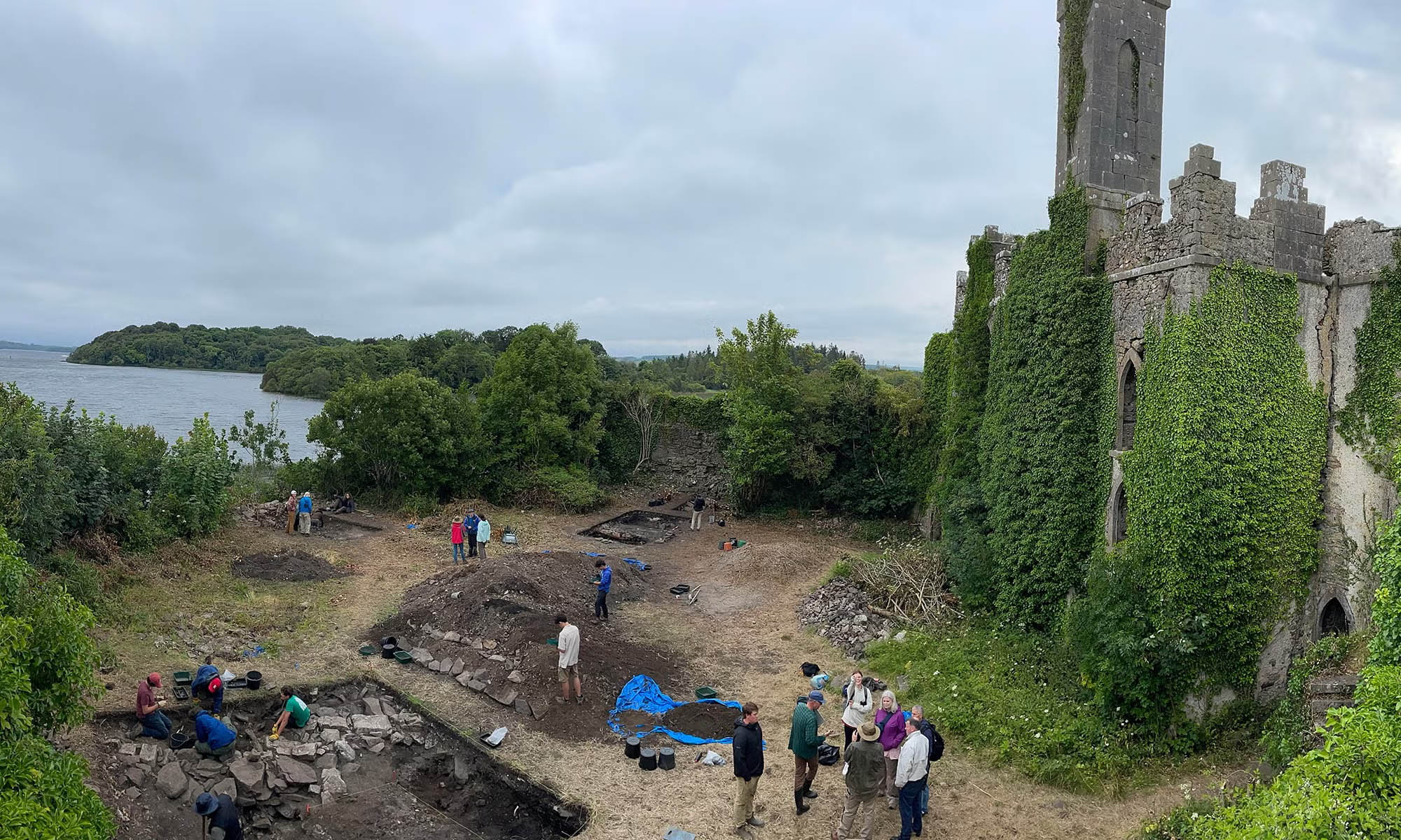 Aerial view of an anthropological site and excavation next to castle ruins in Ireland.