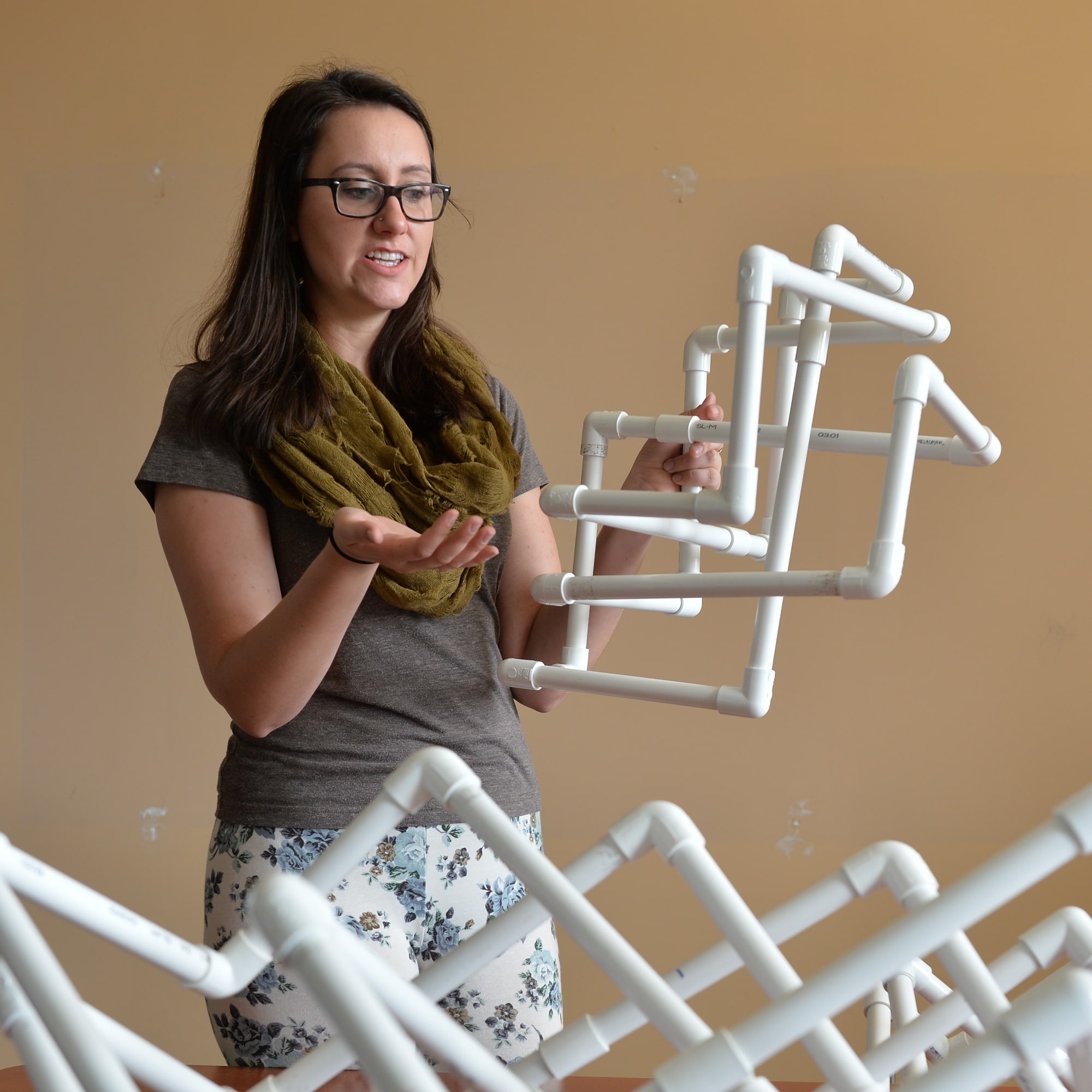 Image of a woman holding a geometric arrangement of pvc pipes.