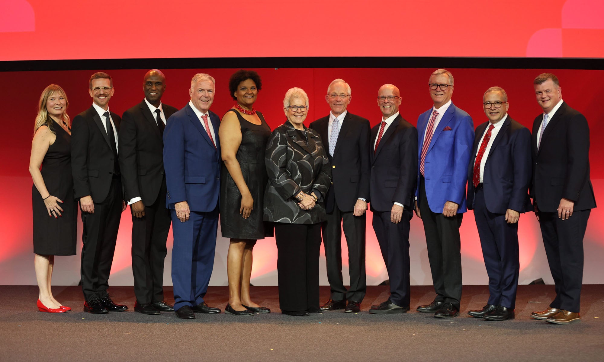 A group of people stand on a stage during a formal event posing for a group photo.