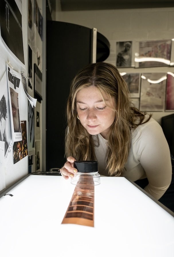 Art history student reviews photos on film with a photo light box