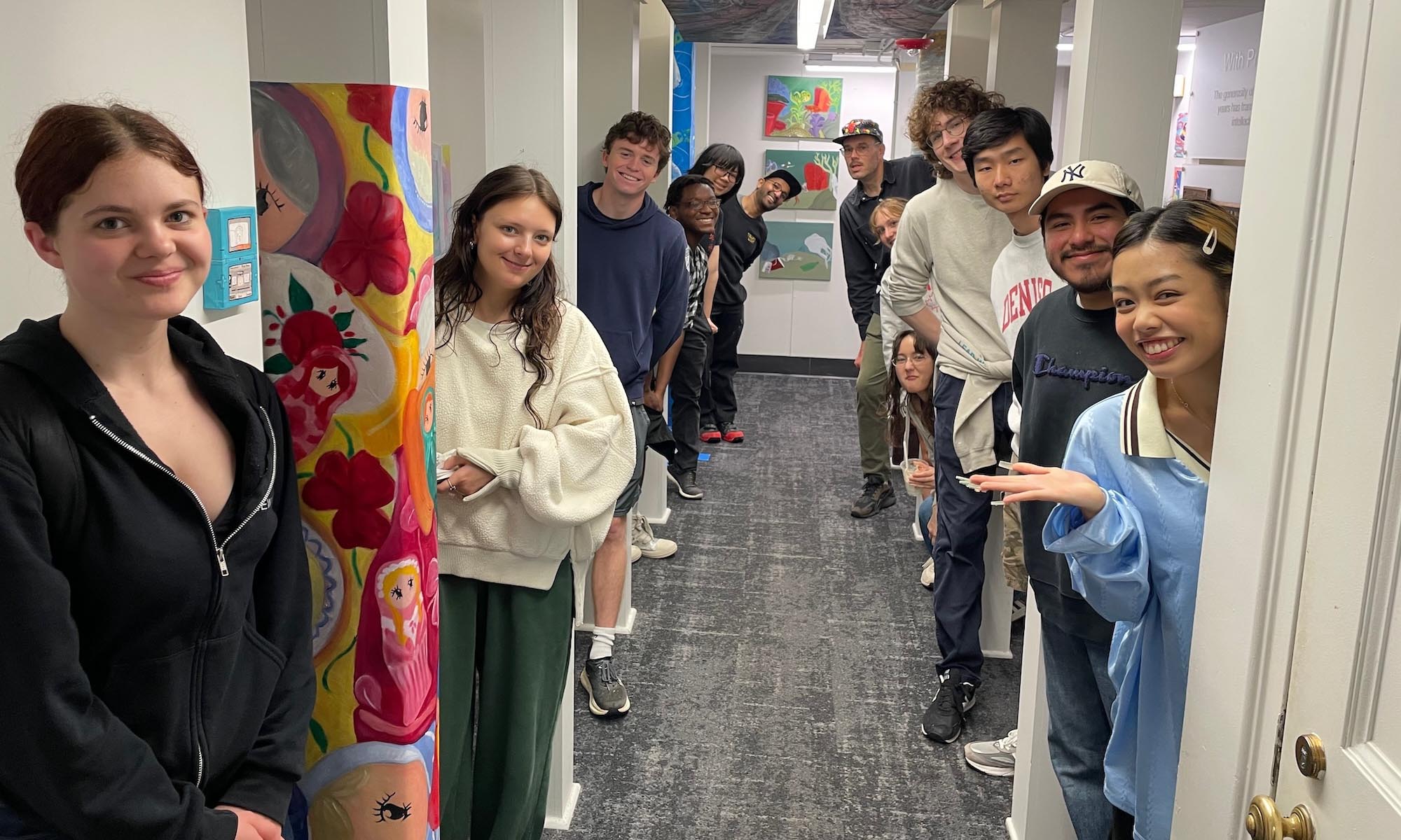 Visual Arts students and faculty pose with their exhibition in the Denison Libraries' first floor throughway space.