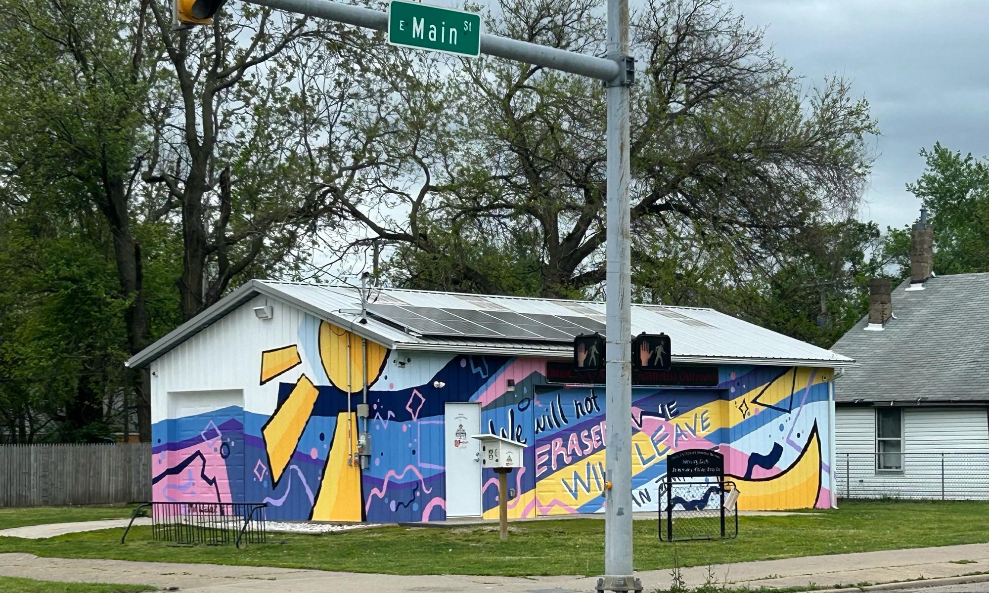 A view of the building from the street corner, showing mural wrapping around two side of the structure.