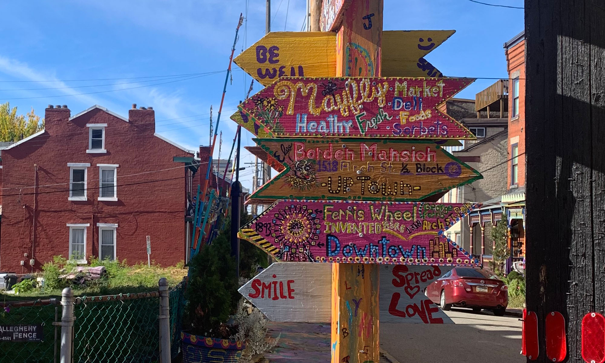Photo of colorfully painted directional wooden signpost, with a half-a-dozen arrows pointing left and right.