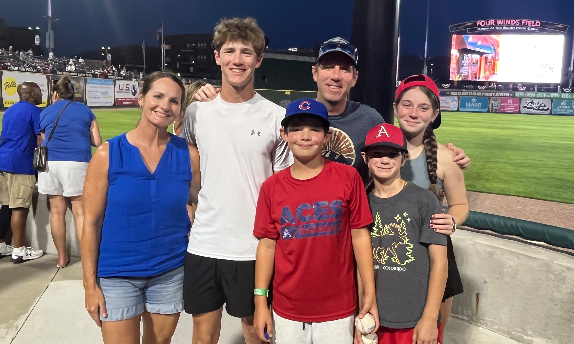 Photo of the Regan family posing at a baseball field during a night game.