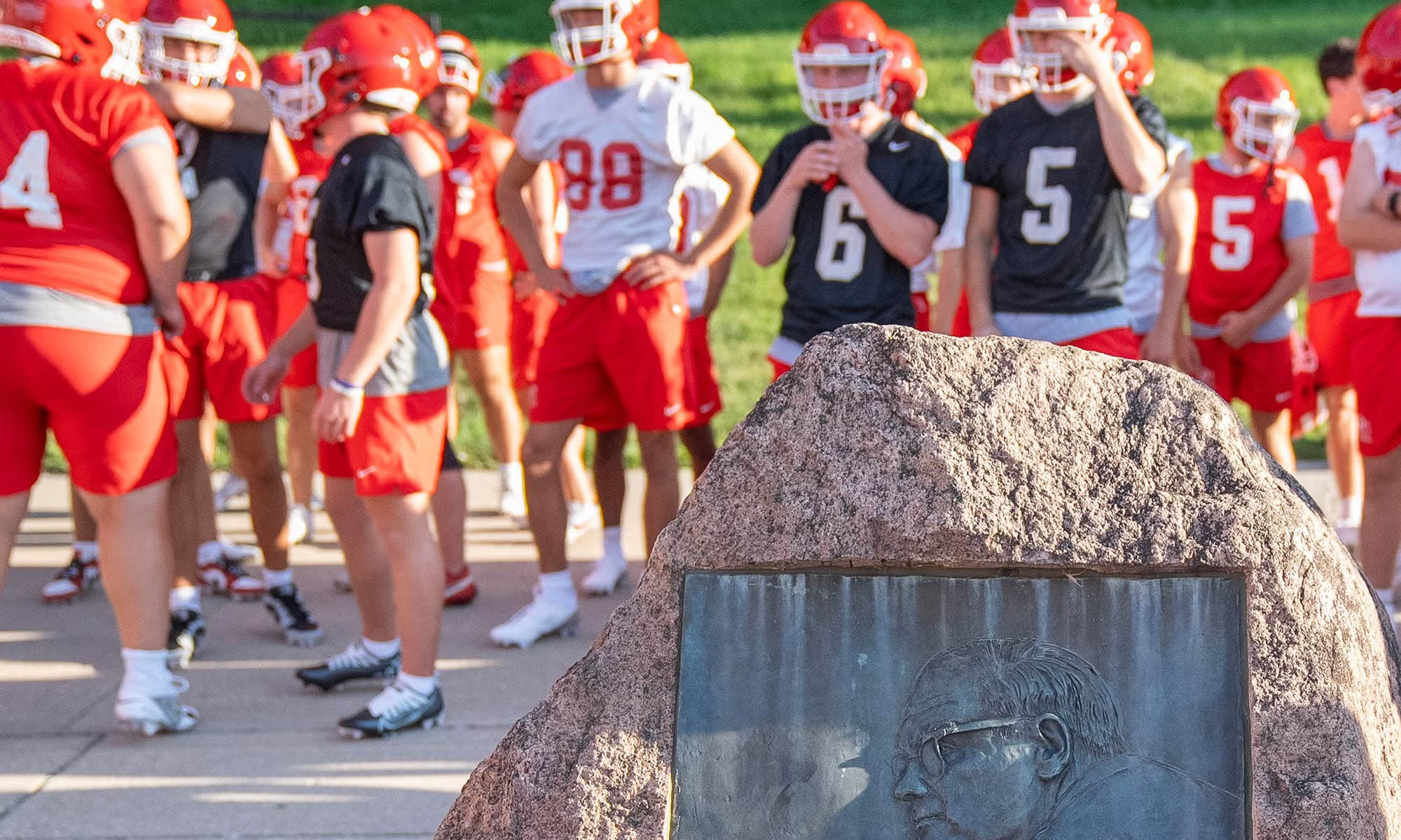 Football team gathering around rock memorial