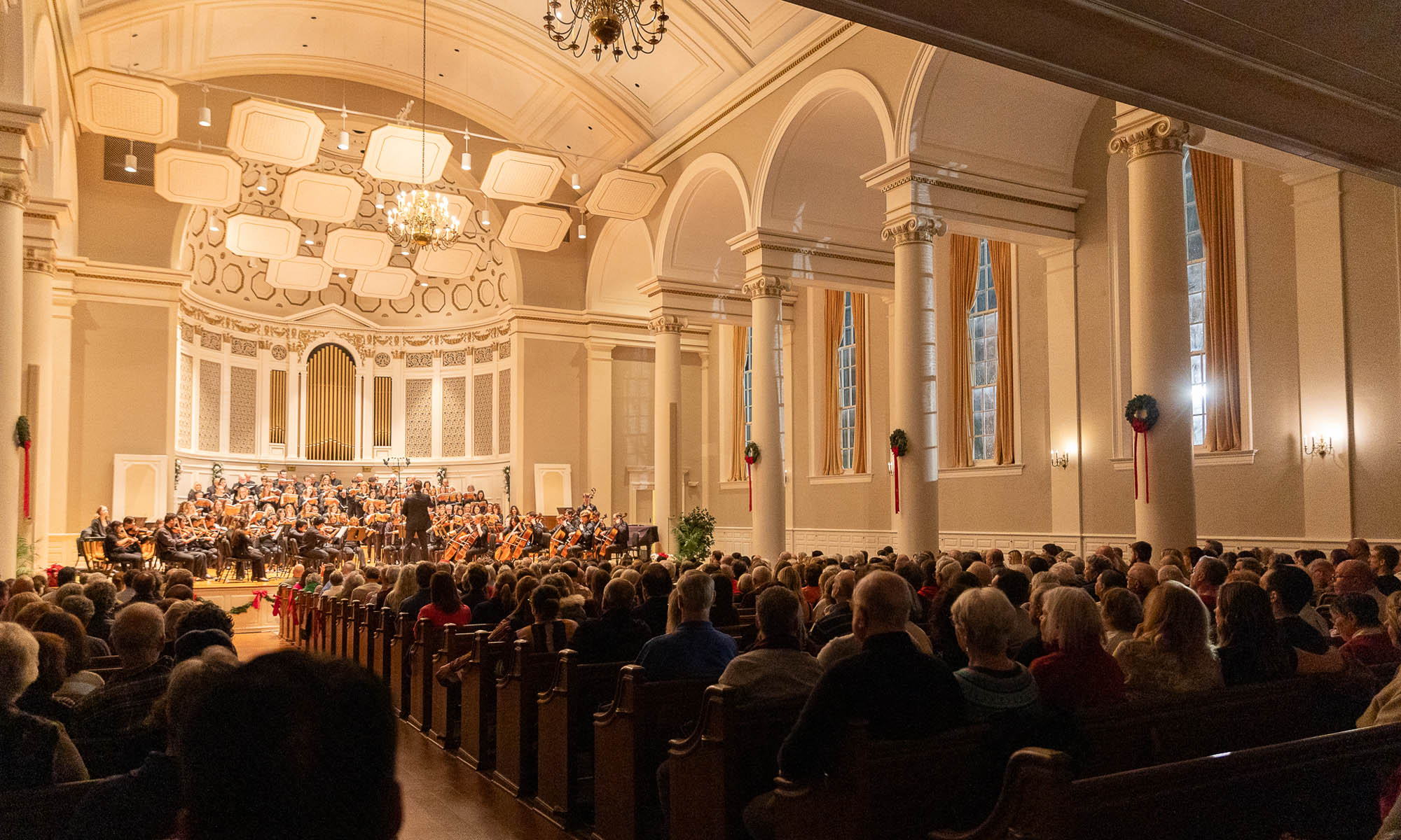 A choir performs in a large chapel space.