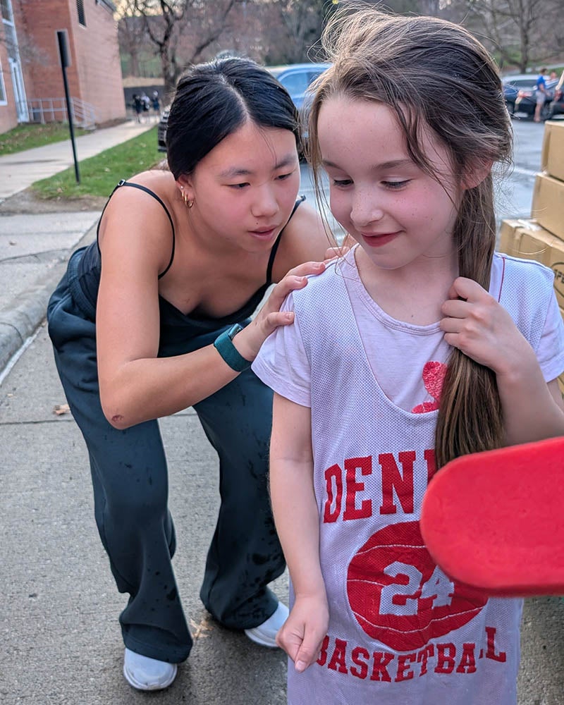Denison women's basketball player Abby Cooch signs a tee shirt for a young basketball fan.