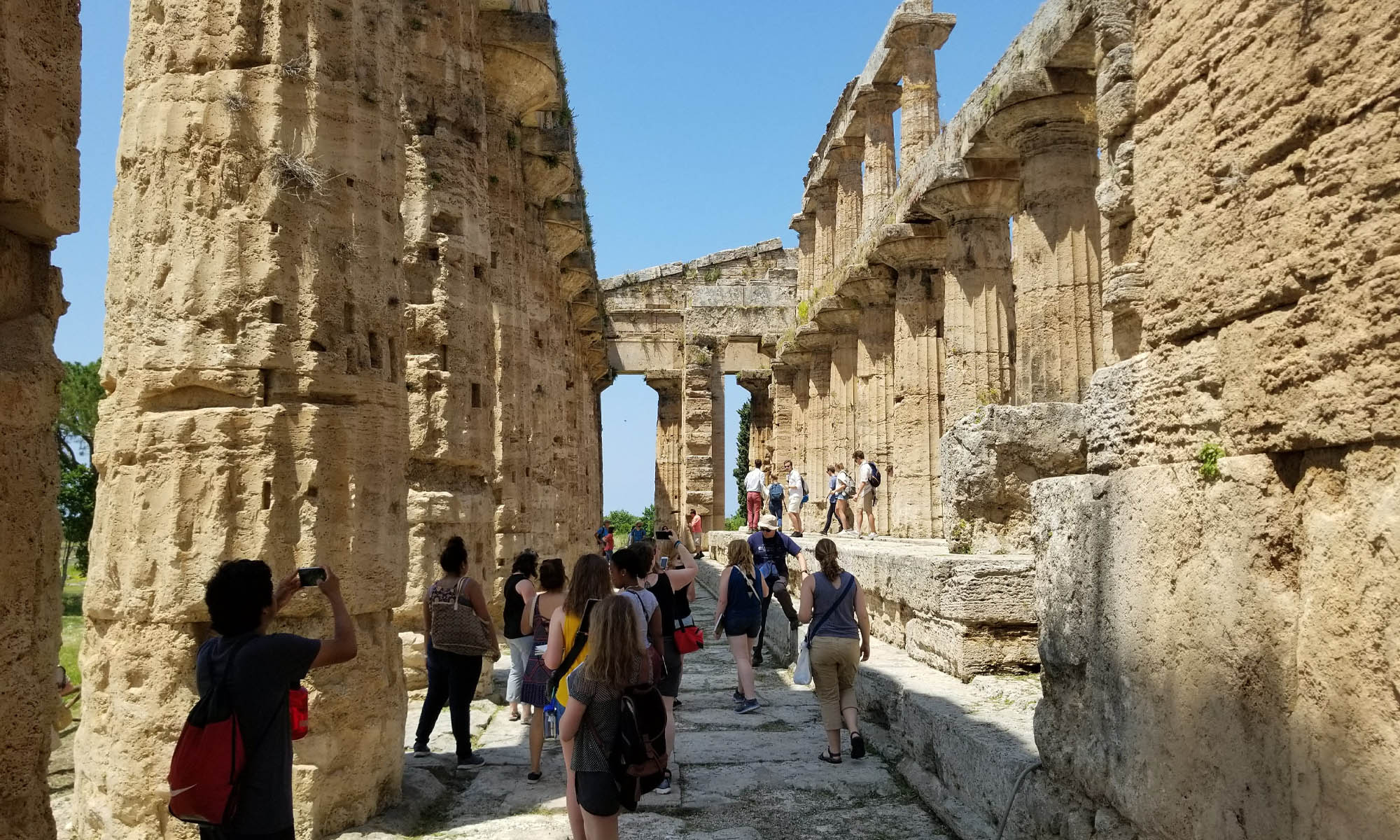 A large group of college students tour a ruined temple.