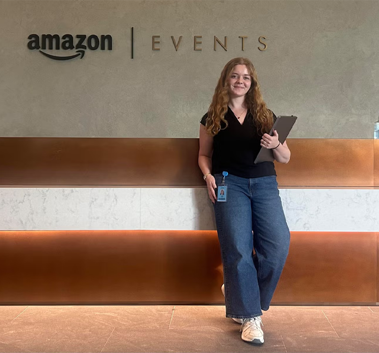 Julia Smith '28 stands in the lobby of the Amazon Events office holding a tablet.