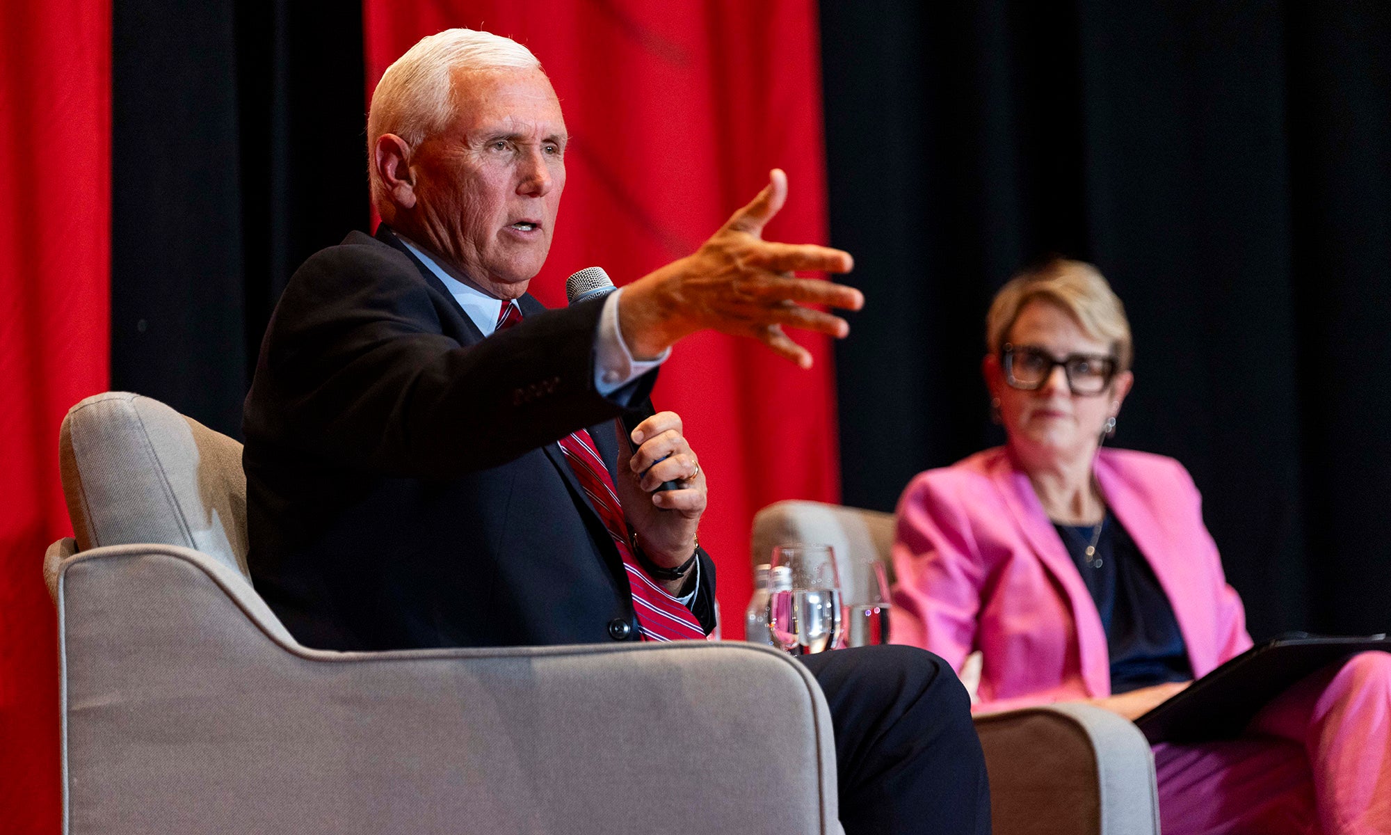 Vice President Mike Pence sits on stage in moderated discussion as a faculty member listens in the background.