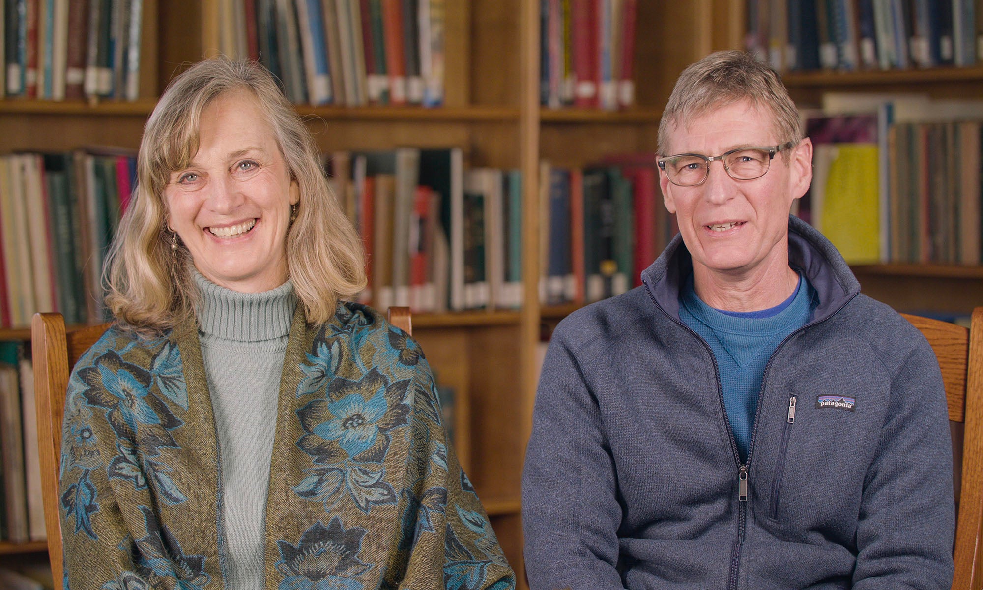 Suzanne and Gary Baker sitting in front of a large library bookcase.