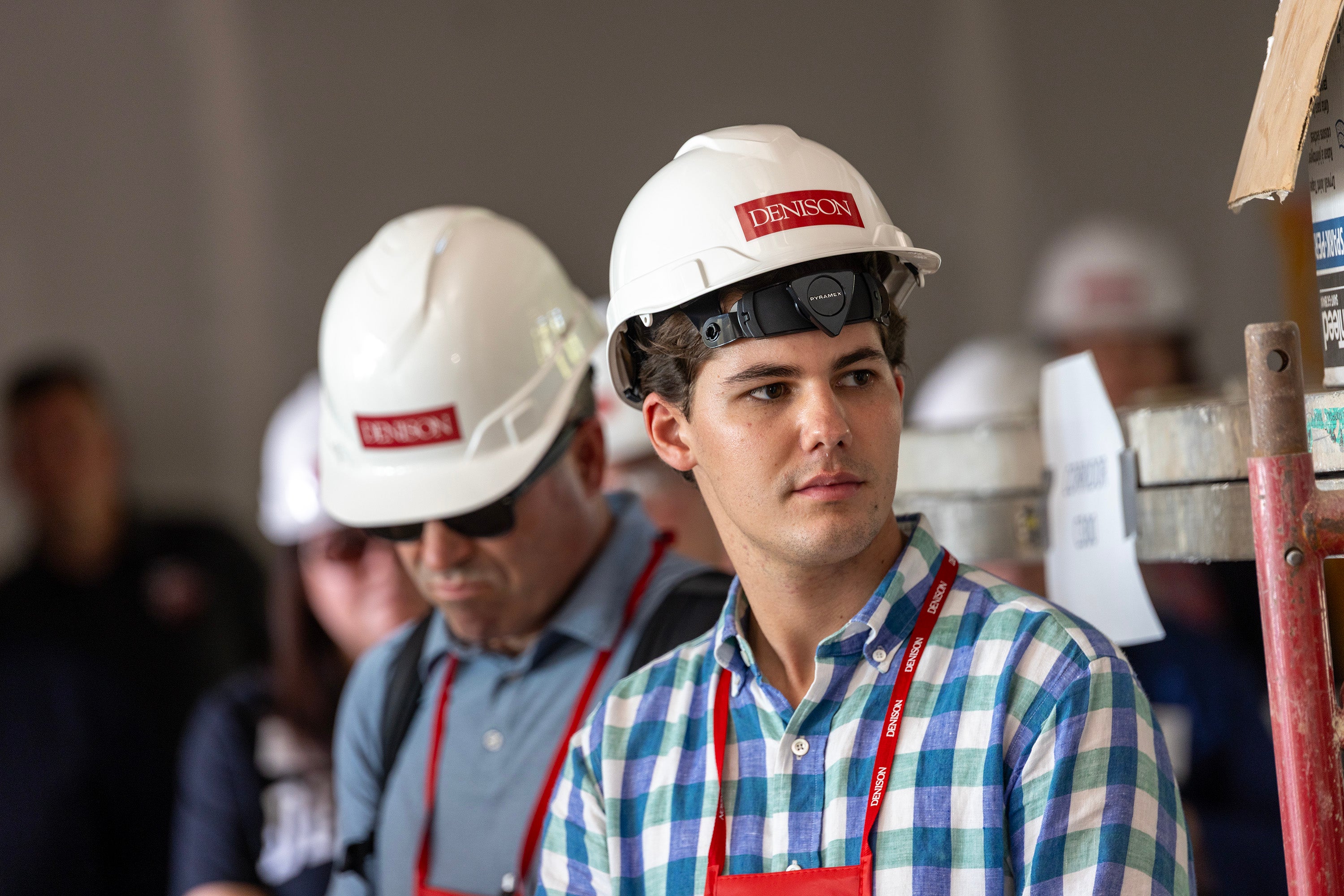 Several people in construction hard hats tour the build site.
