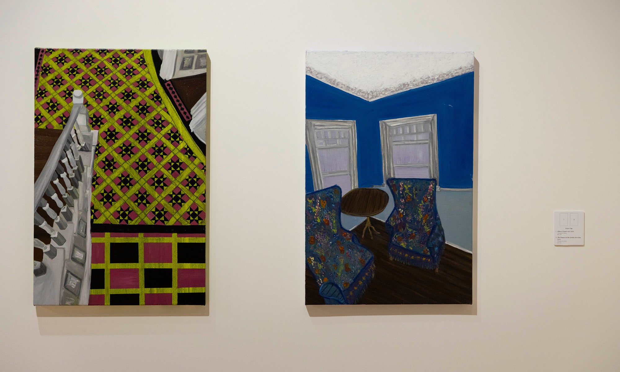 Two paintings hang on a white wall at the Denison Museum art exhibition; the left artwork features abstract geometric patterns, while the right one, titled "The Flowers in the Garden are Gone," depicts a blue room with chairs, a round table, and three windows.
