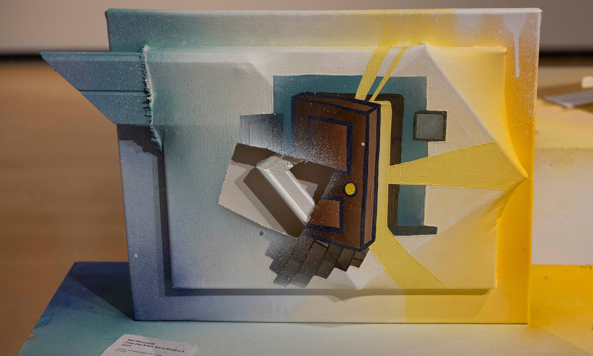 A painting features a stylized brown door with geometric shapes and yellow rays on a blue and yellow gradient background, giving a three-dimensional, abstract appearance—perfect for the "It Was Never Just Then" art exhibition at Denison Museum.