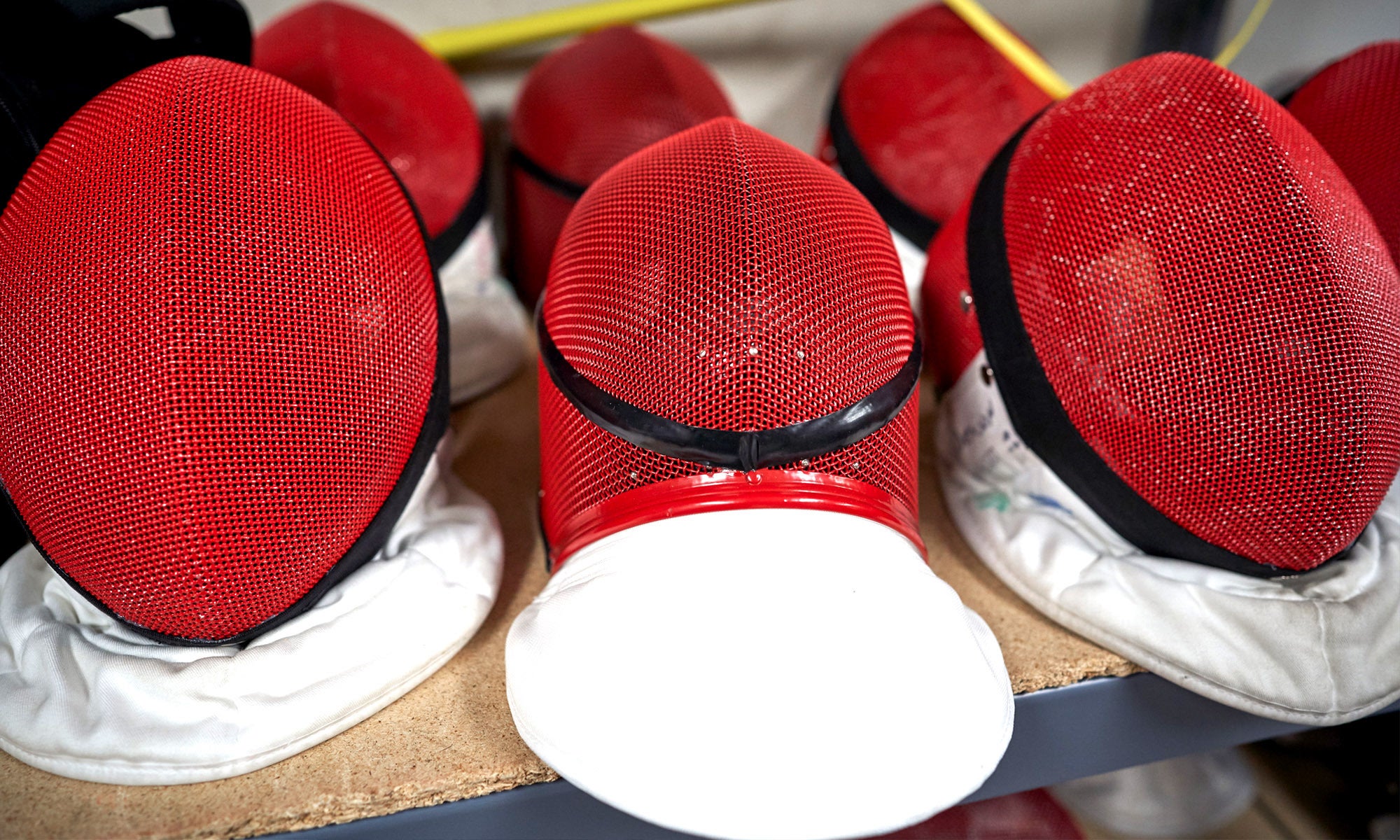 A set of red fencing masks sitting on a table.