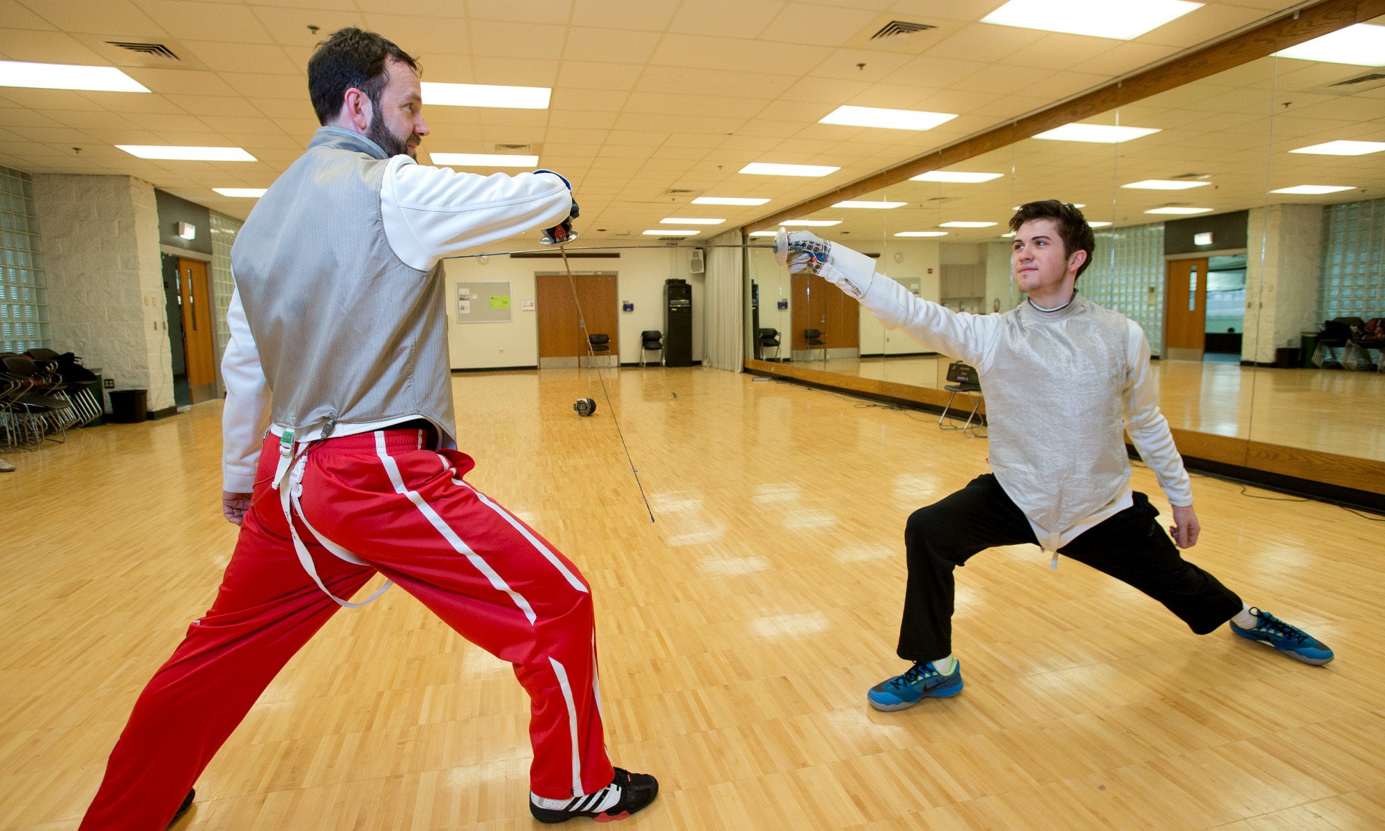 Two fencers working on their technique during a practice.