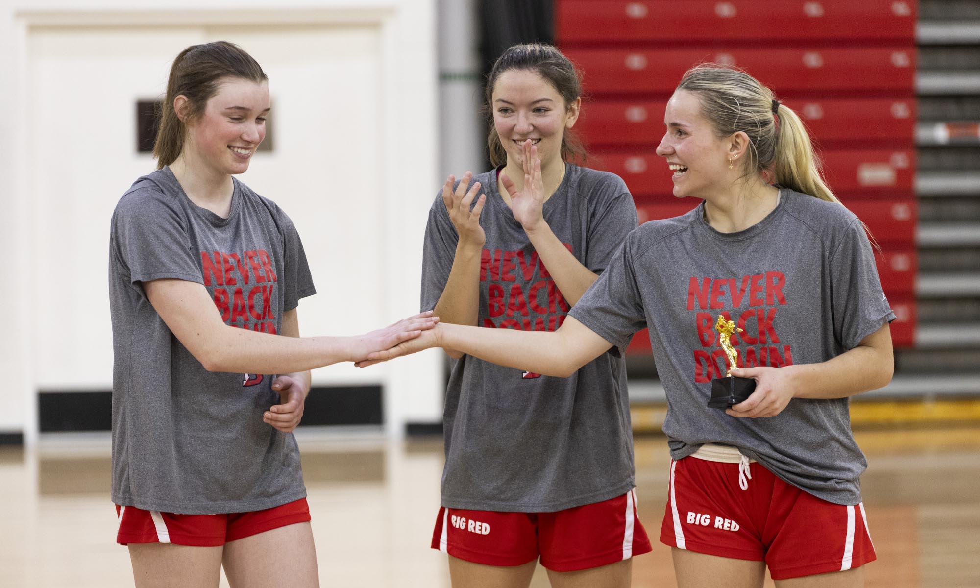 Three women's basketball players in Denison practice gear on the court.
