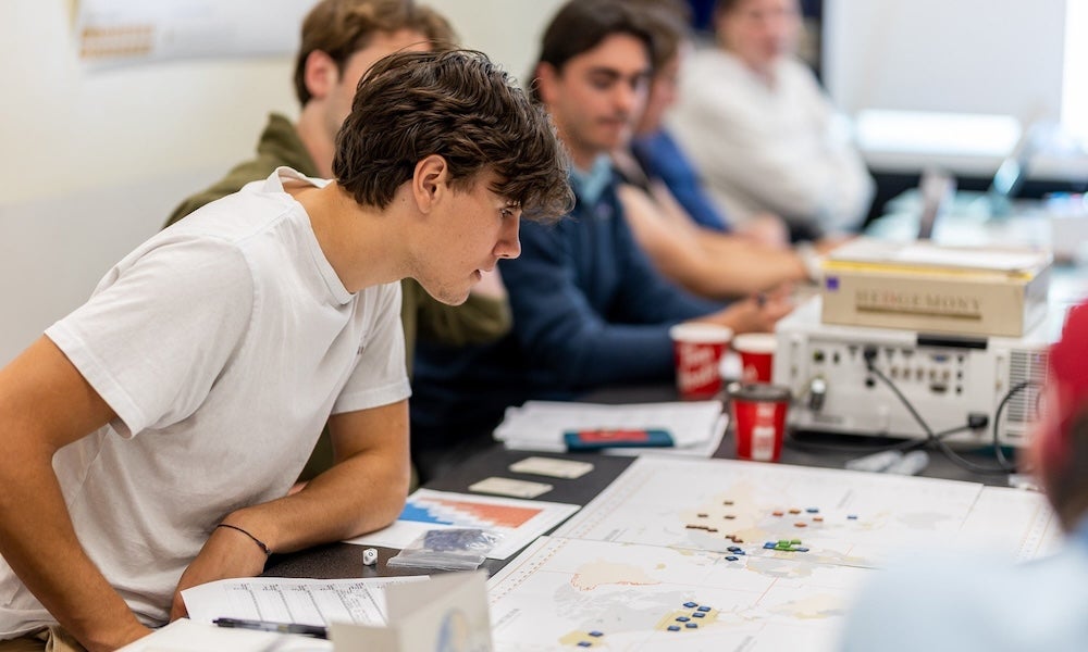 A group of people sit at a table, looking at maps and papers