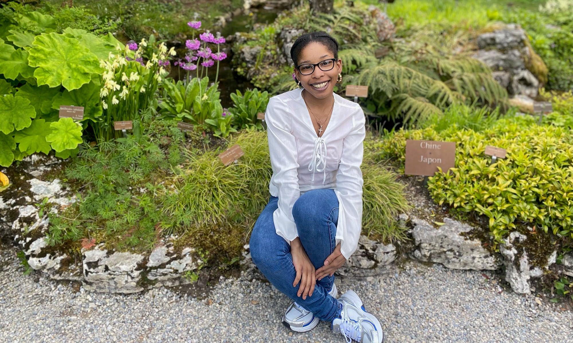 A young woman sits in a garden.