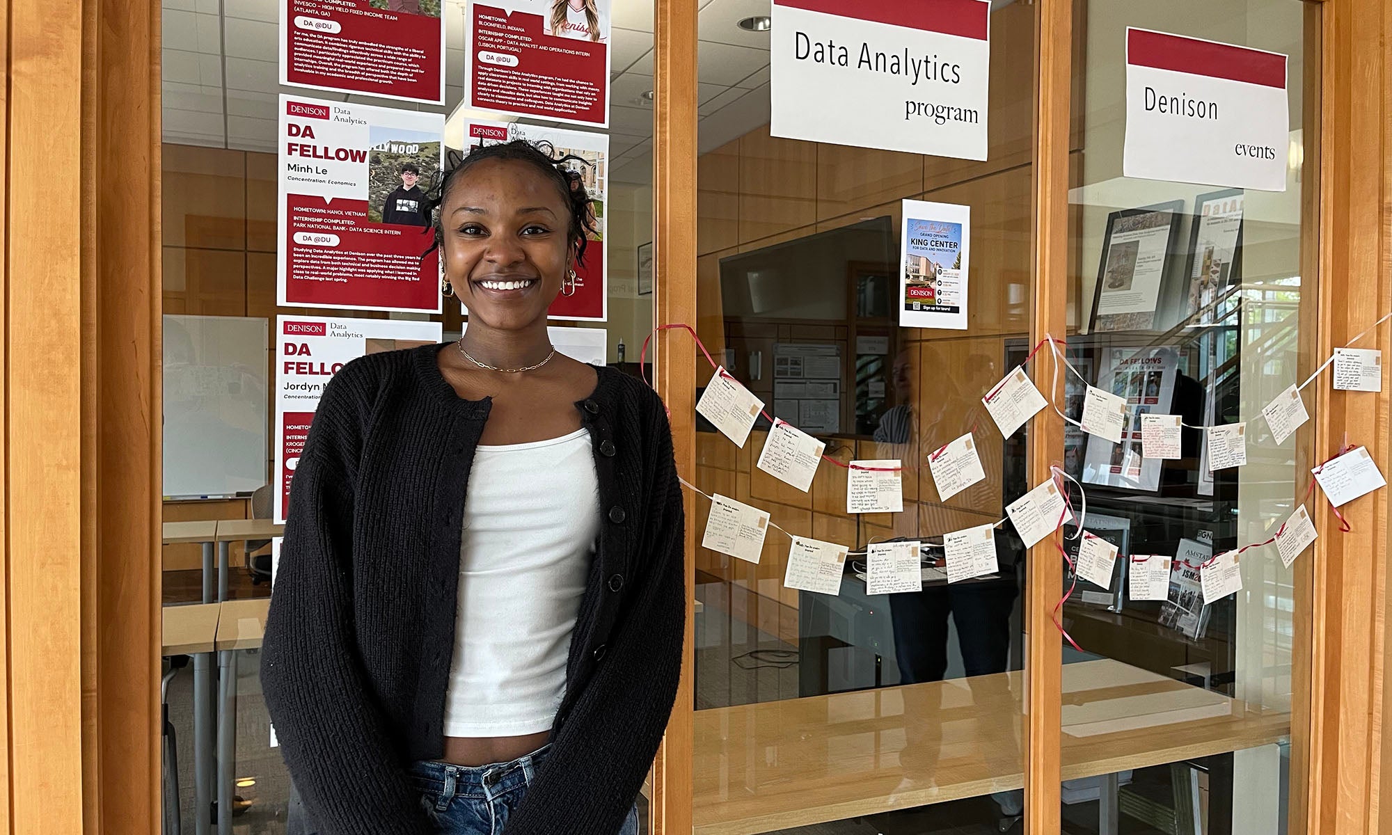 Data Analytics student in front of an office window that's covered with cards