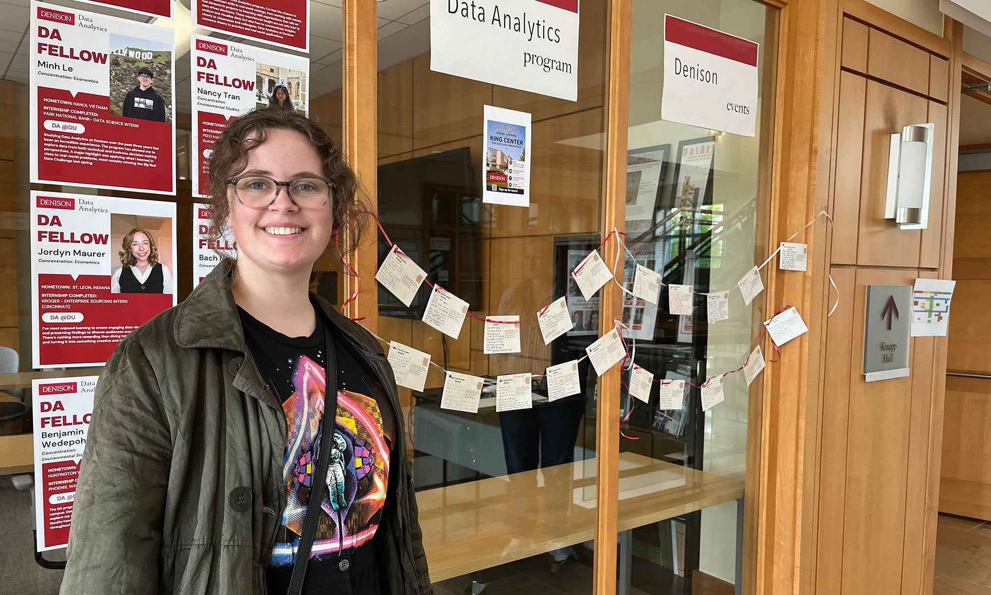Second DA student in front of the department office, which is decorated with cards.