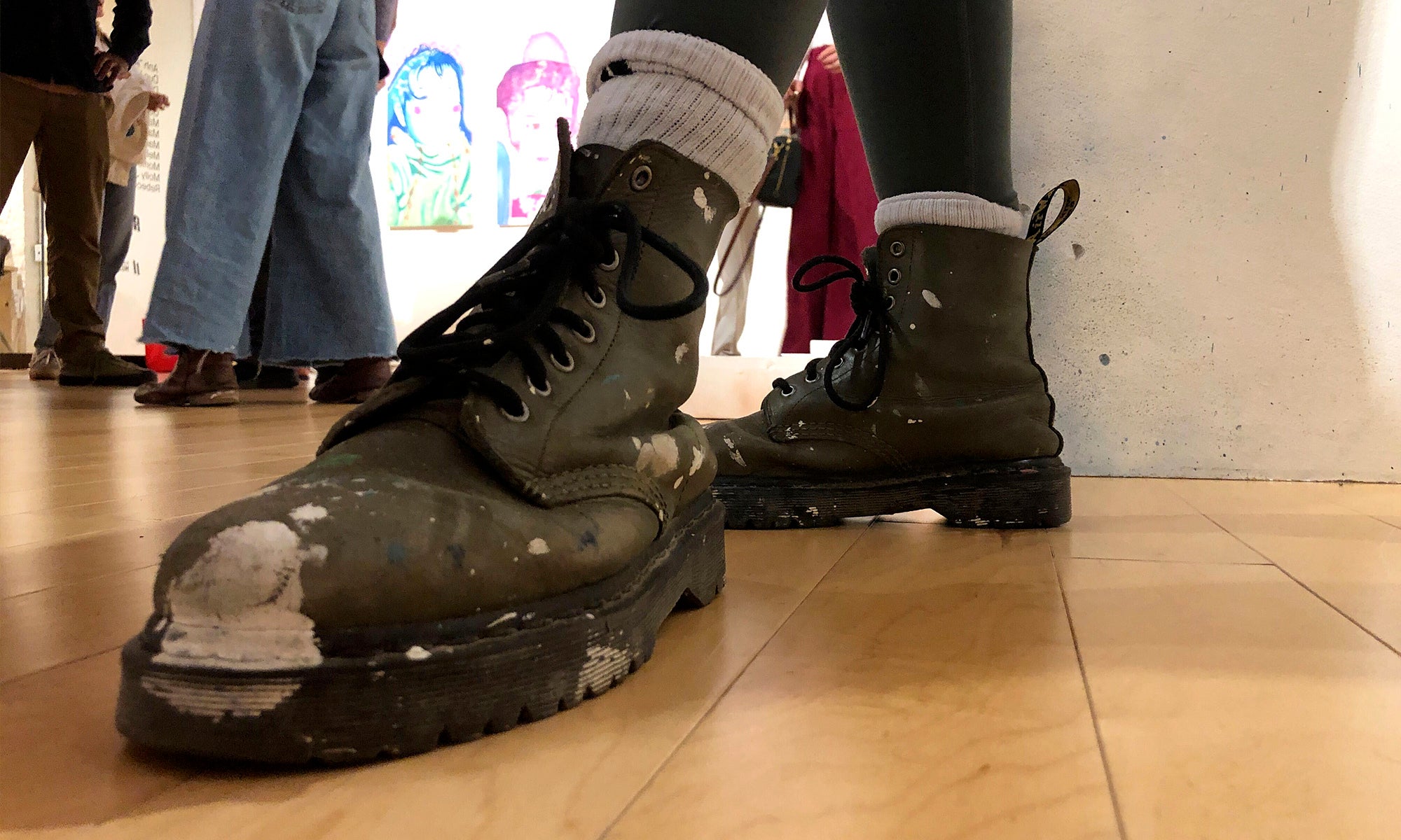A student artists boots are spattered with paint, proof of hard work in the studio.