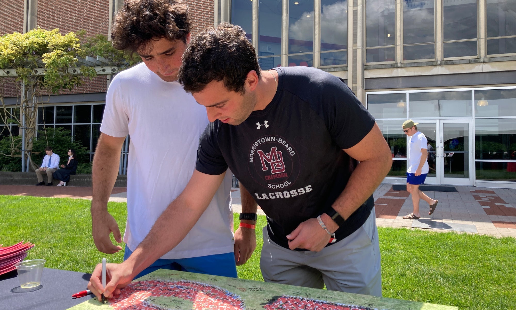 Two Denison seniors sign their names to their class photograph, taken four years ago when they were first-years.
