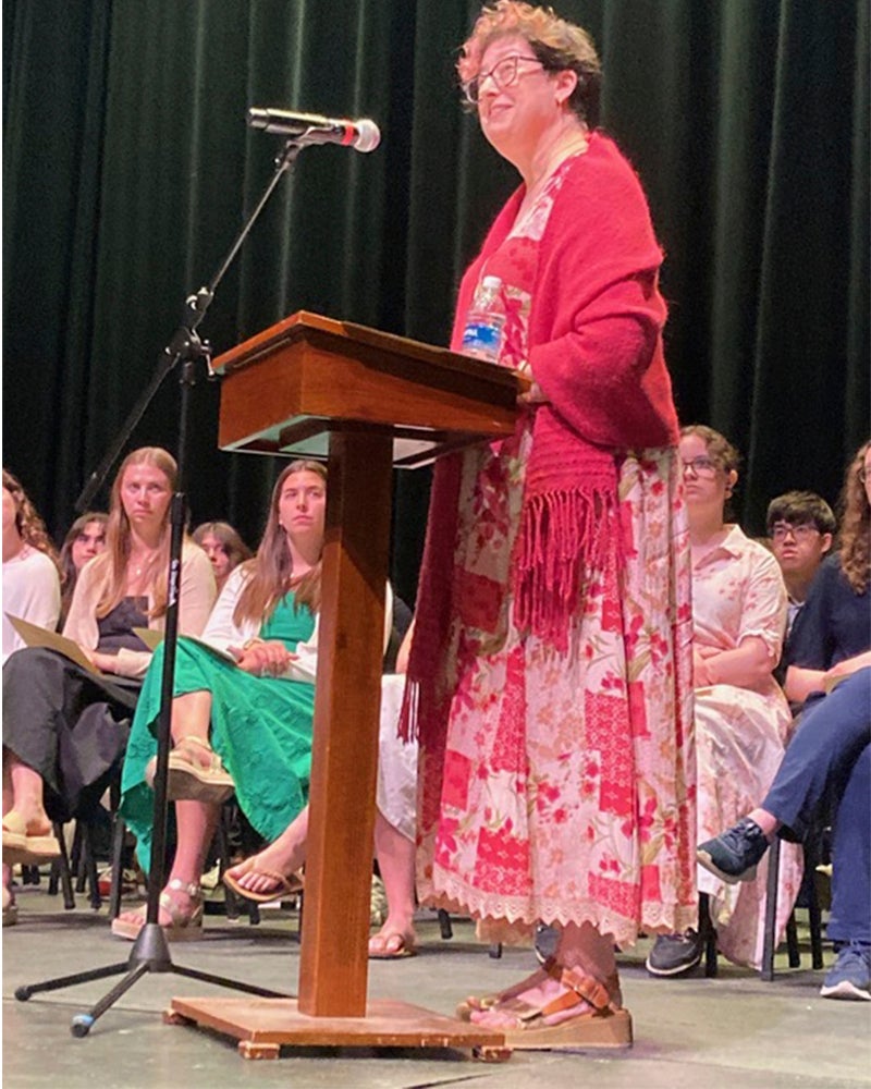 A women in a pink dress stands at podium.