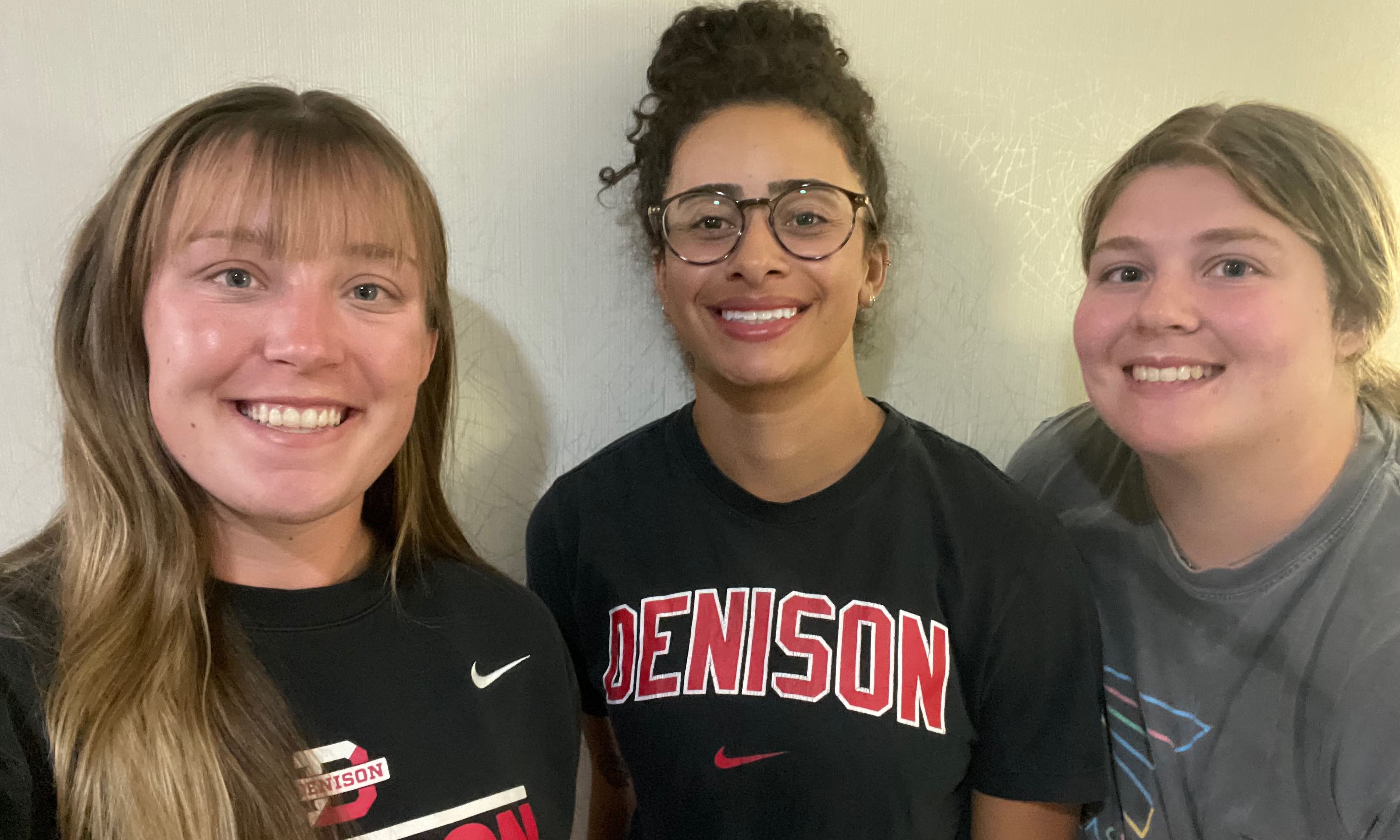 Three young women in Denison gear smile at the camera.