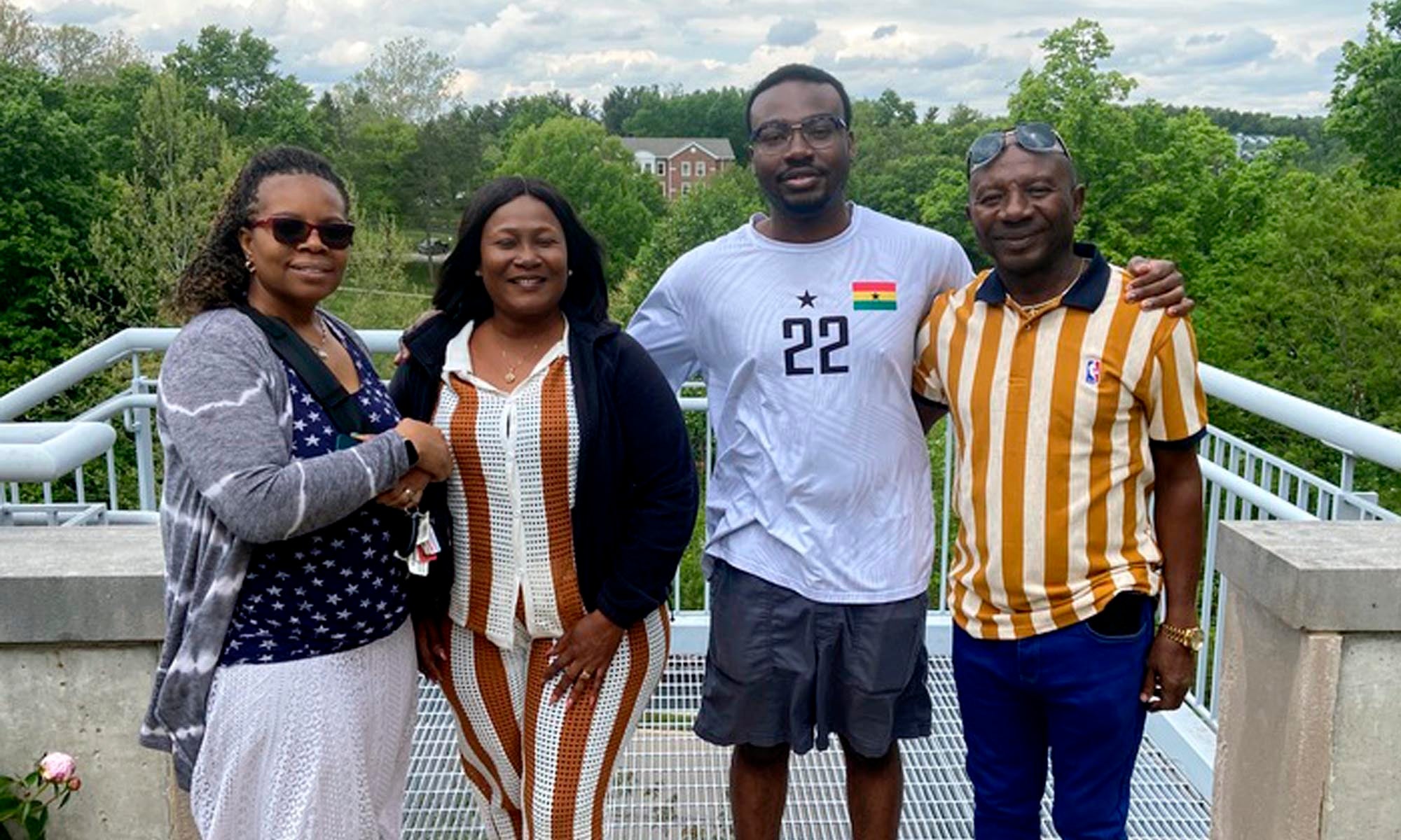 Graduating senior Philip Pearce-Pearson ’26 and his family stand together outdoors, with greenery and trees in the background, posing and smiling for the photo.