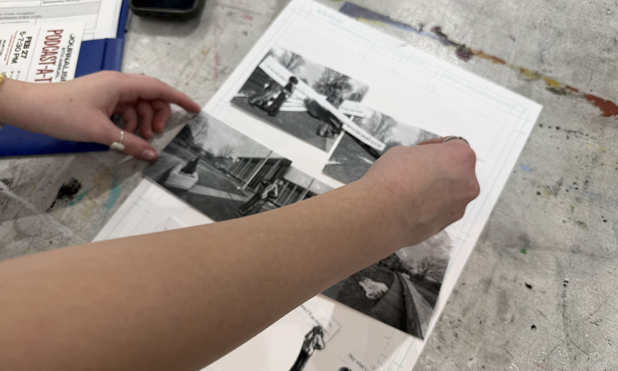 Close up image of a person's hands adjusting black and white photos on a piece of white posterboard.
