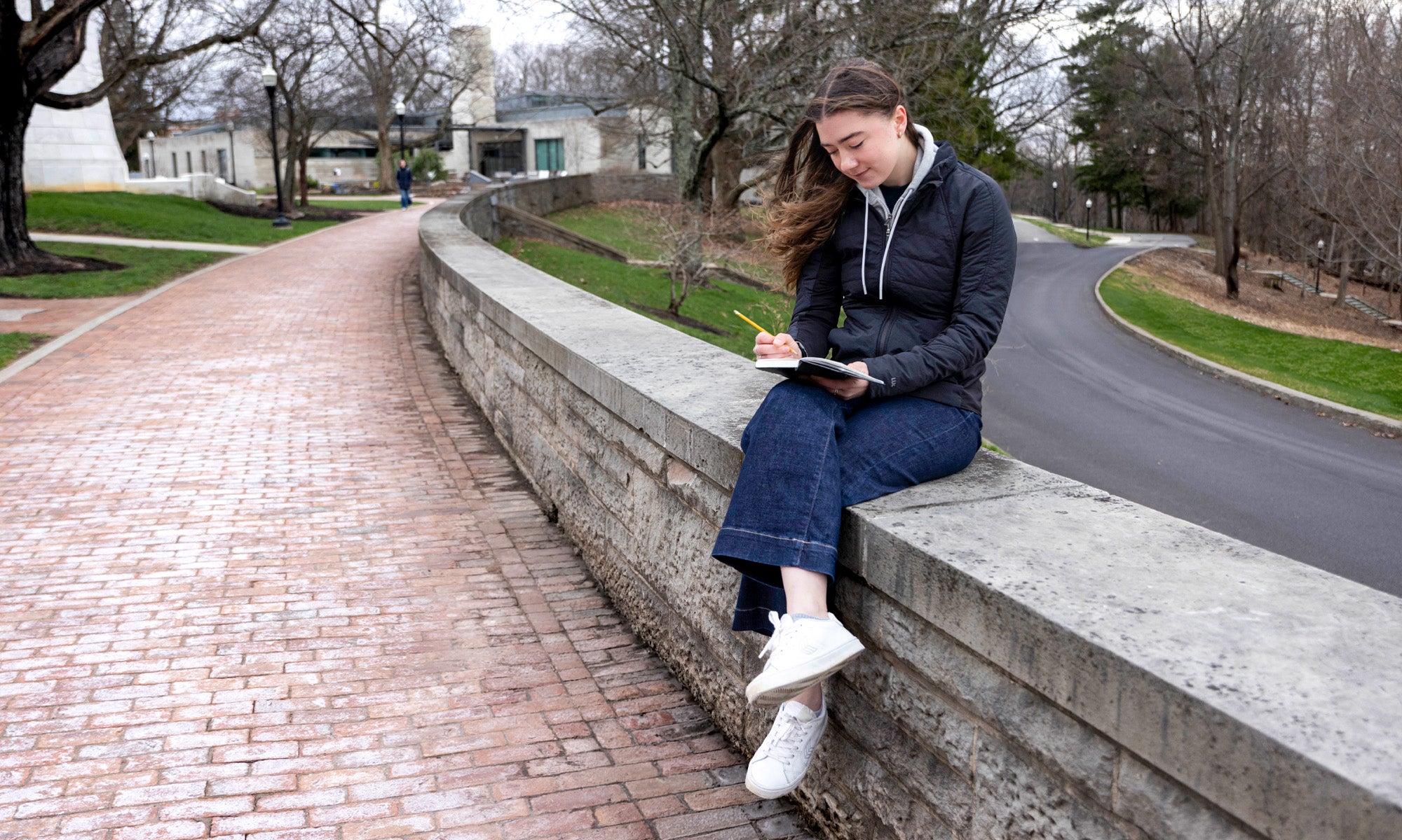 Kelsey Sweetland sits on Chapel Walk writing on a notepad