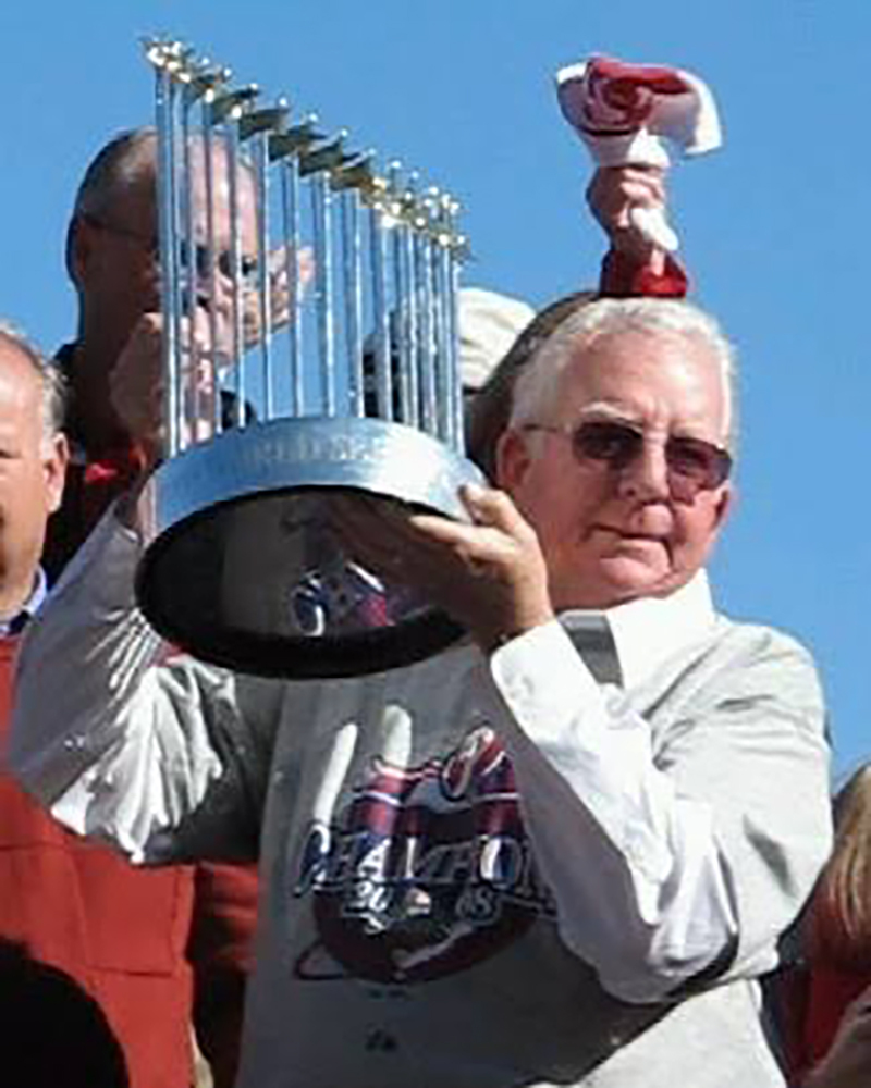 A man holding a World Series trophy overhead.