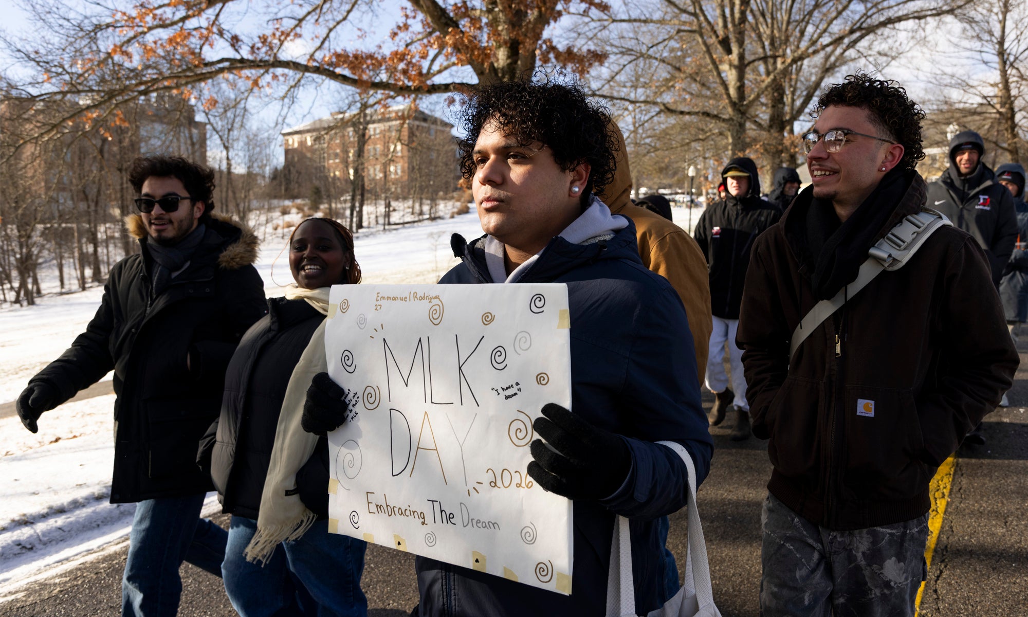 A student carries a sign that says MLK Day in a march across campus.