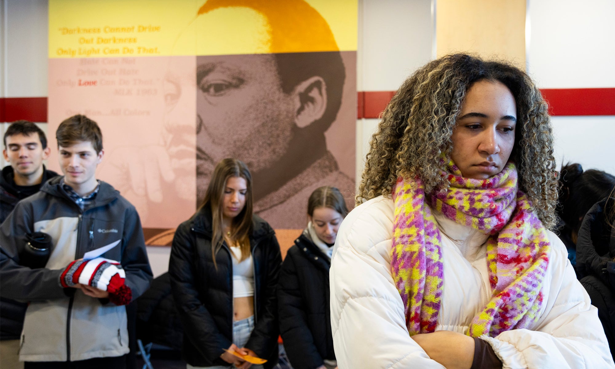 Five people gathered under a poster of Martin Luther King Jr., listening to opening remarks.