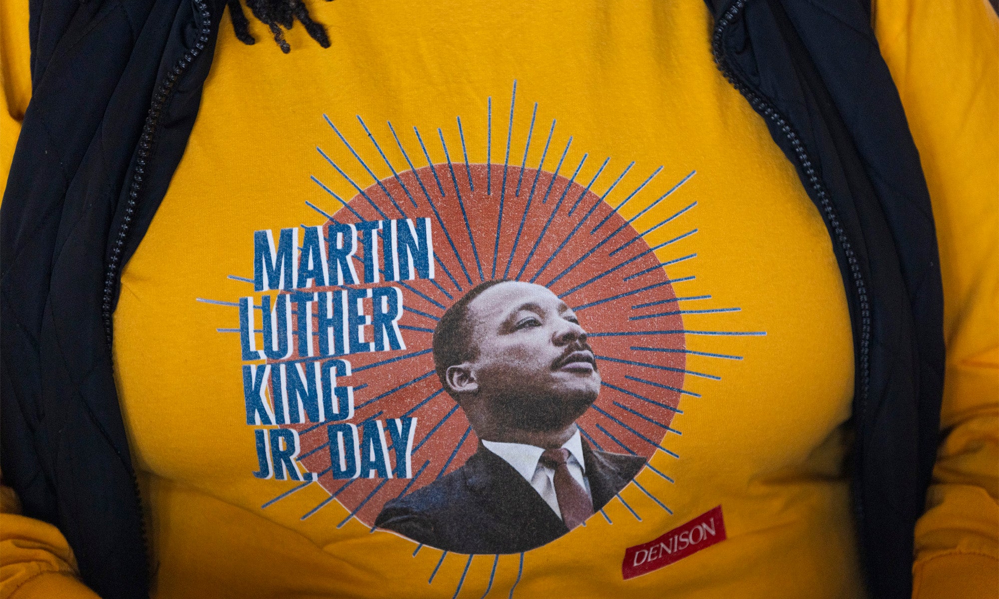 Close-up photo of a yellow sweatshirt with an image of Martin Luther King Jr. in a suit alongside the words "Martin Luther King Jr Day"