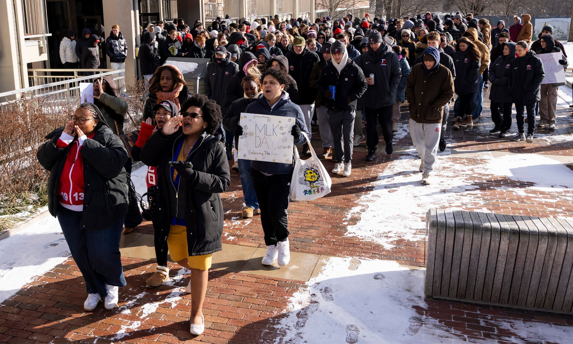 A large group of people march together on a brick path.