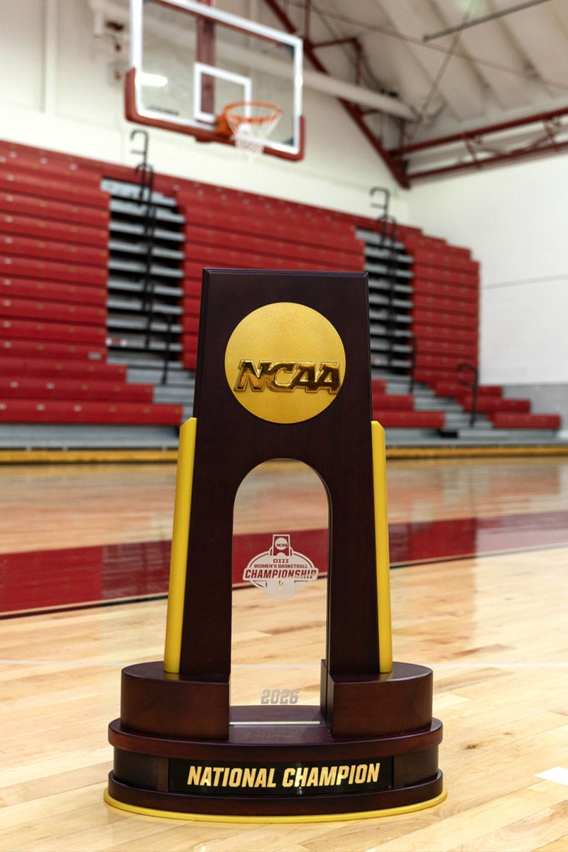 An NCAA championship trophy sitting on a basketball court under a basketball hoop.